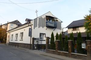 a white building with a balcony on a street at Pensiunea Lor in Sighetu Marmaţiei