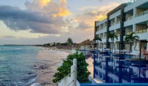 - une vue sur un hôtel et la plage au coucher du soleil dans l'établissement Senses Riviera Maya by Artisan - All inclusive-Adults only, à Puerto Morelos