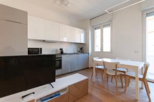 - une cuisine avec des placards blancs, une table et des chaises dans l'établissement YouHosty - Del Castagno 2, à Milan