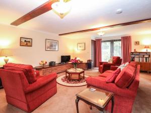 a living room with red furniture and a tv at Walnut Tree Cottage in Great Yarmouth
