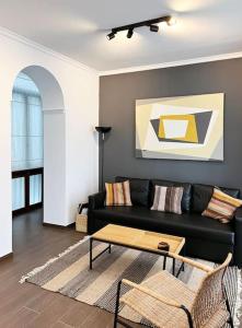 Casa Odisea Cádiz في كاديز: غرفة معيشة مع أريكة سوداء وطاولة