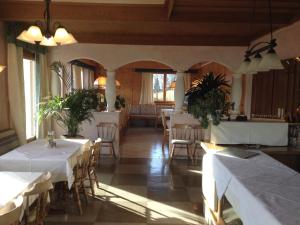 restauracja z białymi stołami, krzesłami i oknami w obiekcie Pension Schlossberg w mieście Mittersill