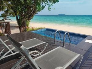 a deck with a table and chairs and the beach at Phi Phi Holiday Resort-SHA Extra Plus in Phi Phi Islands