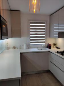 a white kitchen with a sink and a window at App 5 pers, parking, 3mn RER A, 40 mn du centre de Paris, Cergy le Haut in Cergy
