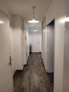 an empty hallway with white walls and wooden floors at App 5 pers, parking, 3mn RER A, 40 mn du centre de Paris, Cergy le Haut in Cergy