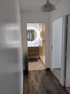 um corredor com uma casa de banho com um lavatório e um espelho em App 5 pers, parking, 3mn RER A, 40 mn du centre de Paris, Cergy le Haut em Cergy