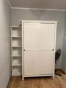 a white closet with white shelves in a room at Apartament TURKUSOWY in Kalisz