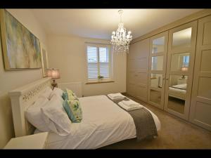 um quarto com uma grande cama branca e um lustre em Luxury Waddington Cottage, Ribble Valley em Waddington