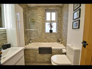 a bathroom with a tub and a toilet and a window at Luxury Waddington Cottage, Ribble Valley in Waddington