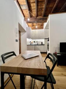 a wooden table and chairs in a room with a kitchen at La dimora della Giudecca - 13 in Cuneo