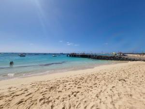 a beach with people in the water and a pier at Daisal Apartment - 2 bedroom apartment with balcony near the beach & city center, perfect for nomads, travellers, families, watersports! in Santa Maria