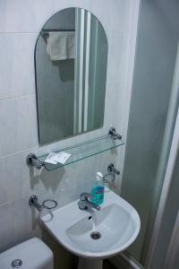 ein Badezimmer mit einem Waschbecken, einem Spiegel und einem WC in der Unterkunft Olimpija Hotel & SPA in Daugavpils