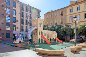 a playground in front of a building with a clock tower at Under the Olive Trees in Historic Center of Malaga in Málaga