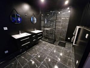 La salle de bains noire est pourvue d'un lavabo et d'une douche. dans l'établissement Suite Coquine avec jacuzzi YaoSpa60, 