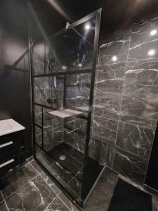 La salle de bains est pourvue d'une douche et d'un mur en pierre. dans l'établissement Suite Coquine avec jacuzzi YaoSpa60, 