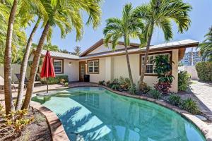 a swimming pool with palm trees in front of a house at Anna Maria Island Surfside Bungalow in Holmes Beach