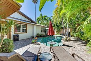 a backyard with a pool with a table and a umbrella at Anna Maria Island Surfside Bungalow in Holmes Beach