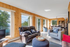 sala de estar con sofá y TV en MontFJORD - Chalets, SPA et vue - ChantaFJORD #2 en Sacré-Coeur-Saguenay