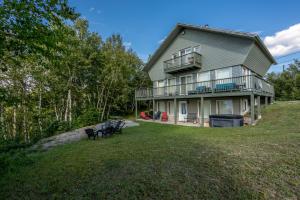 a house on a hill with chairs in the yard at MontFJORD - Chalets, SPA et vue - ChantaFJORD #2 in Sacré-Coeur-Saguenay