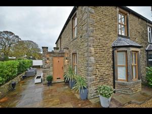 a brick house with a patio and a wooden door at Luxury Waddington Cottage, Ribble Valley in Waddington