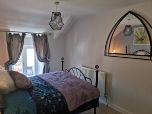 a bedroom with a bed and a large mirror at Dare Valley Cottage Ex miners cottage Near Zip World Pen y fan Waterfalls in Aberdare
