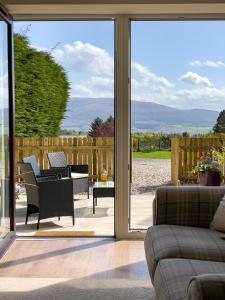 a living room with a sliding glass door at Taighsona Bothy, Speyside - amazing views! in Archiestown