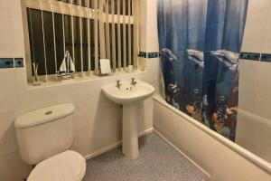 a white bathroom with a toilet and a sink at Benllech Sea View bungalow, Dog Friendly sleeps 6 in Benllech