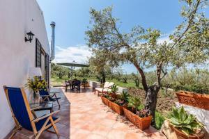 patio ze stołami, krzesłami i drzewem w obiekcie Villa Lorenza Private beach w mieście Caronia