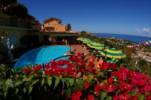 ein Resort mit einem Pool, der mit roten Blumen und Sonnenschirmen geschmückt ist. in der Unterkunft Hotel Orizzonte Blu in Tropea