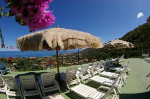 eine Gruppe von Gartenstühlen und ein Sonnenschirm in der Unterkunft Hotel Orizzonte Blu in Tropea