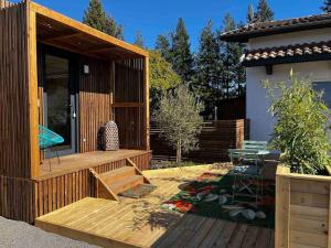 een houten terras met een tafel en stoelen op een huis bij Le Lodge in Belin-Beliet
