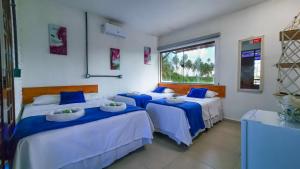 a room with three beds with blue and white sheets at Pousada Brisa e Mar in Praia do Frances +78 photos