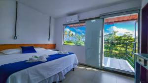 a bedroom with a bed and a large window at Pousada Brisa e Mar in Praia do Frances