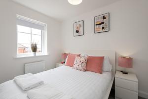 a white bed with pink pillows and a window at Bell Road in Durham