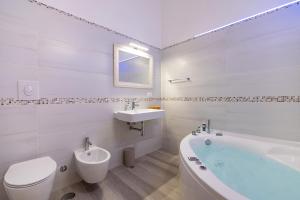 a white bathroom with a tub and a toilet and a sink at Palazzo Giannotte Suite & Spa in Ostuni +71 photos
