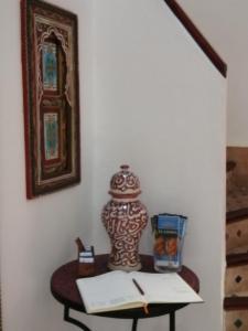 une table avec un livre et un vase sur elle dans l'établissement Riad Siham, à El Jadida