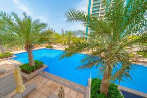 a swimming pool with palm trees and a building at Bright Sunny Dubai Apartment- Private Terrace Garden- Canal Views- Pool & Gym in Dubai