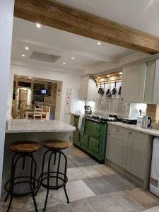 a kitchen with a counter and two stools in it at Big fireplace aga hot tub wet room barn garage in Llanelli