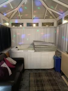 Kleines Zimmer mit Badewanne und Sofa in der Unterkunft Big fireplace aga hot tub wet room barn garage in Llanelli