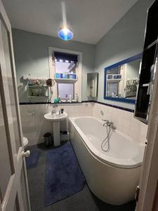 ein Badezimmer mit einer großen Badewanne und einem Waschbecken in der Unterkunft Big fireplace aga hot tub wet room barn garage in Llanelli