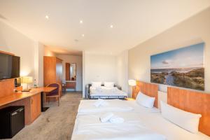 ein Hotelzimmer mit 2 Betten und einem TV in der Unterkunft Hotel Königslinie in Sassnitz