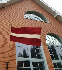 een vlag aan de zijkant van een bakstenen gebouw bij Hotel Melturi in Melturi