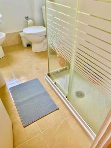 a bathroom with a toilet and a glass shower at Luz, sol y arena in Rota