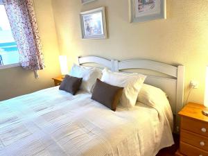 a bedroom with a white bed with pillows and a window at Luz, sol y arena in Rota