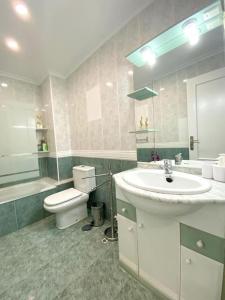een badkamer met een wastafel, een toilet en een spiegel bij Letty's House in Santa Pola