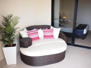 a wicker chair with pink and white pillows on it at Edge Apartments Cairns in Cairns