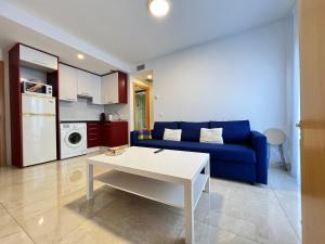 un soggiorno con divano blu e tavolo bianco di Fabuloso apartamento completo centro ciudad a Móstoles