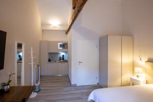 a bedroom with a white bed and a kitchen at Auberge des Grands Bois in Buchillon