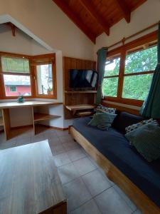 1 dormitorio con 1 cama, escritorio y ventanas en Departamento Orillas del Pocahullo en San Martín de los Andes
