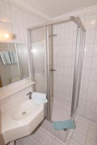 a white bathroom with a shower and a sink at Schiederhof in Mittersill